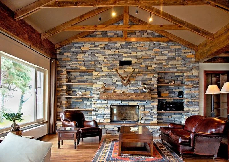 Odun şöminesi etrafına döşenmiş, rustik görünümlü açık kahve rengi kaplama ile kış atmosferi. Rustik şömine dekorasyonu doğal taş kaplama örneği